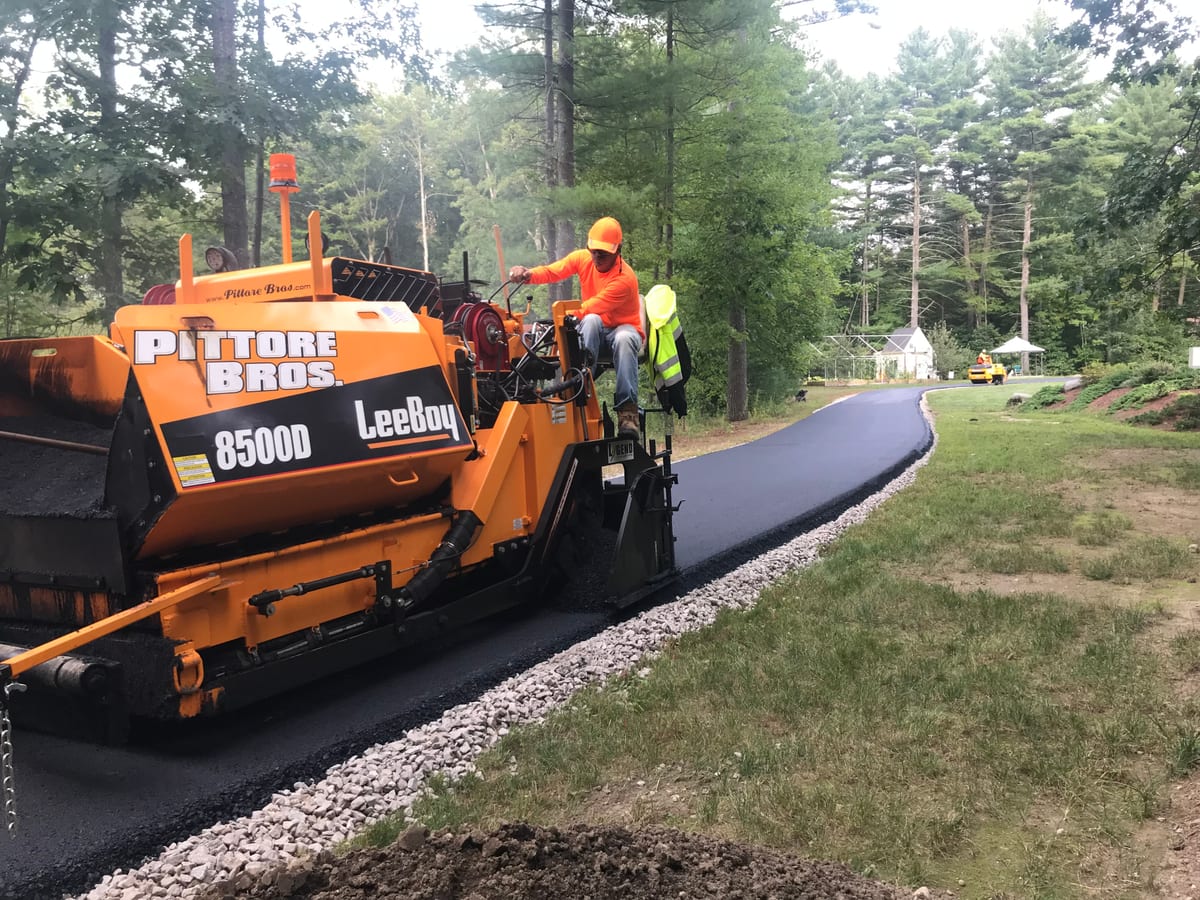 Pittore Brothers crew paving a new residential asphalt driveway curving through a wooded property